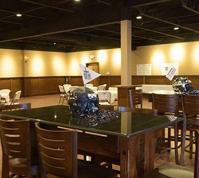 Empty restaurant dining area with wooden tables, chairs, and warm overhead lighting