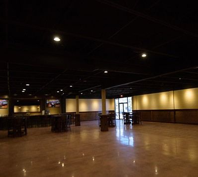 Empty dimly lit banquet hall with polished wooden floor and tables along the walls