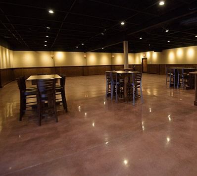 Empty banquet hall with polished floor, round tables, and warm ceiling lights
