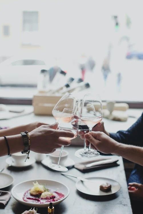 a group of people are toasting with wine glasses at a table .