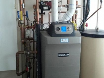 A home heating system with a boiler, copper pipes, and water heater in a utility room.
