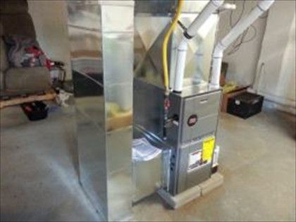 Furnace with ducts in a basement. Gray metal with yellow gas line and white PVC pipes.