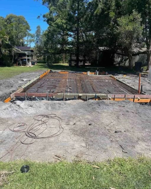 A Concrete Slab Is Being Poured In A Yard In Front Of A House — Tuncote Concrete Constructions in Salamander Bay, NSW