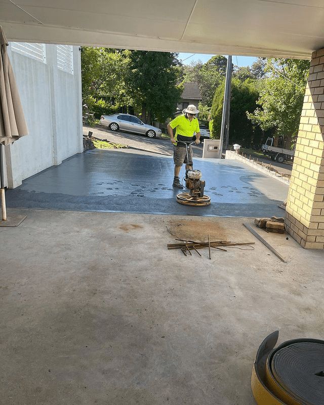 A Man Is Using A Machine To Polish A Concrete Driveway — Tuncote Concrete Constructions in Salamander Bay, NSW
