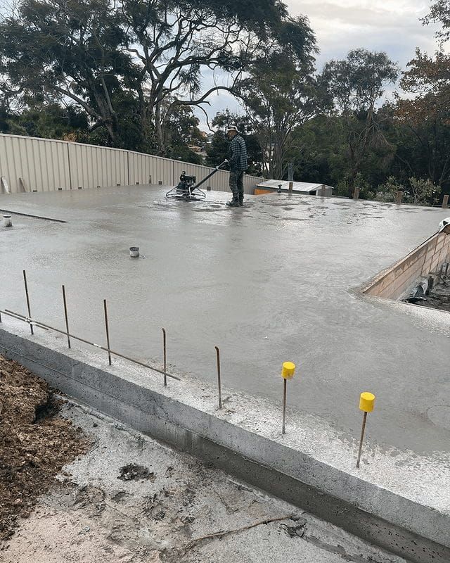 A Man Is Using A Machine To Level A Concrete Floor — Tuncote Concrete Constructions in Nelson Bay, NSW