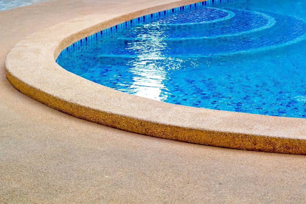 A Swimming Pool With A Curved Edge And Steps Leading Into It — Tuncote Concrete Constructions in Raymond Terrace, NSW