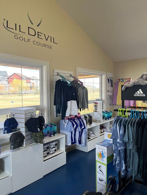 Inside a golf shop: clothing racks, shelves with merchandise, and a