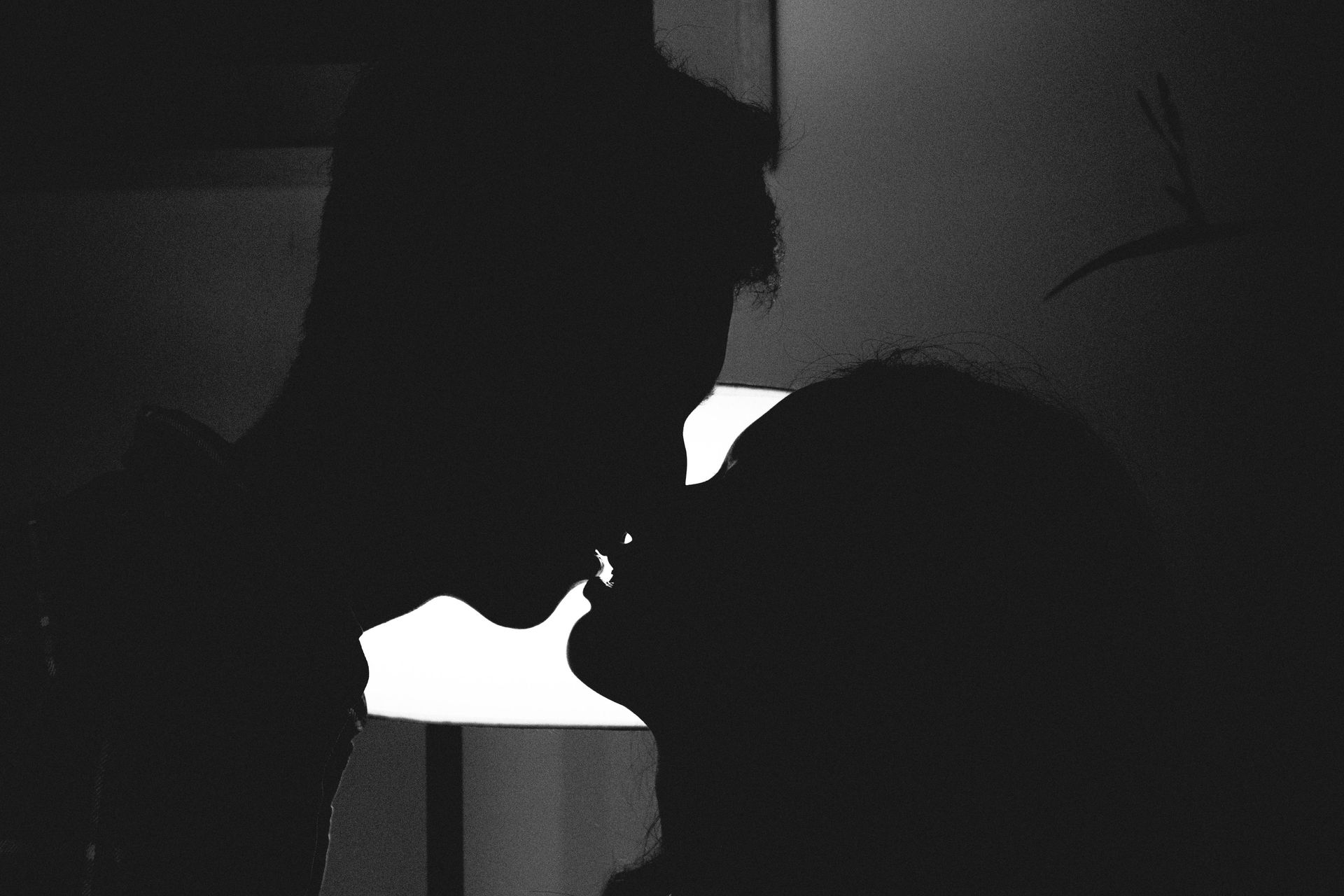 A man and a woman are kissing in a dark room.