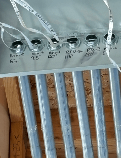Close-up of labeled blue water pipes and fittings mounted on a wall.