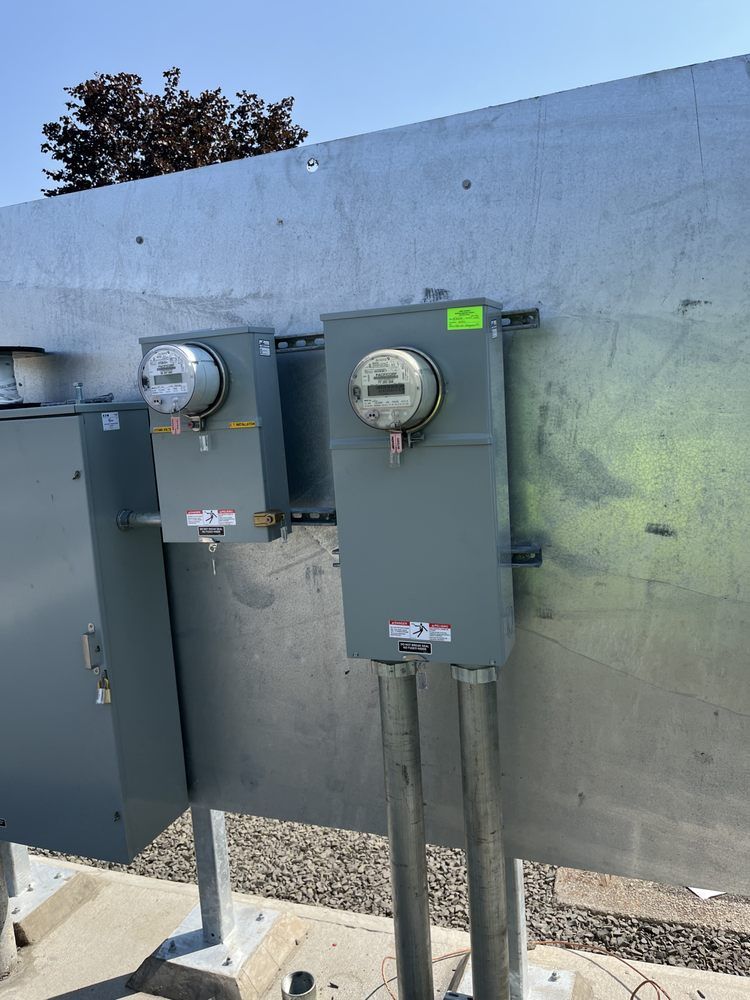 Two gray electrical meter panels mounted on a concrete wall with conduits running downward.