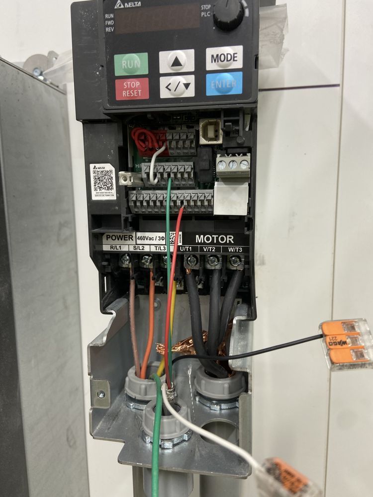 Open electrical control panel with wires, relays, and a keypad on a tiled wall