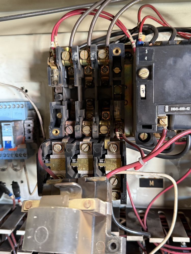 Electrical control panel with relays, wires, and a large black breaker switch.