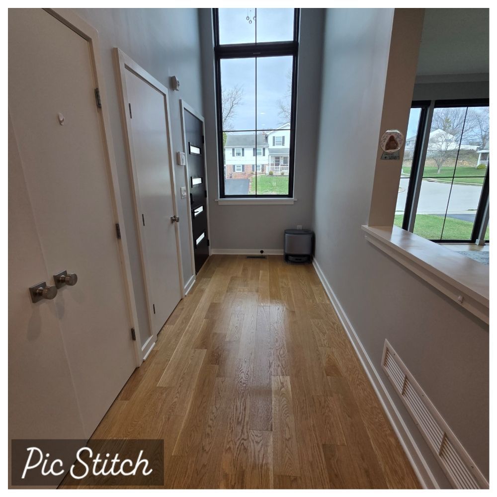 Hallway with light wood floor, white walls, window, and a small trash bin by the far wall.