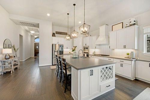Bright modern kitchen with white cabinets, island, pendant lights, and open dining area