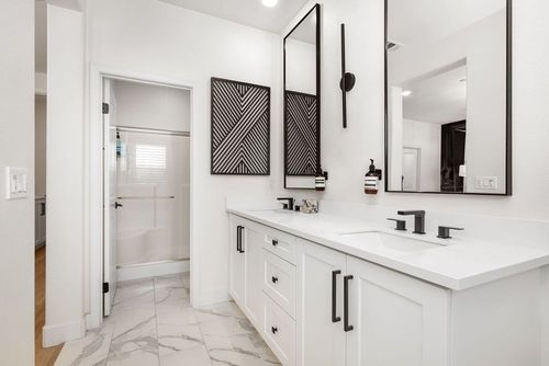 Modern white bathroom with double vanity, large mirror, and walk-in shower.