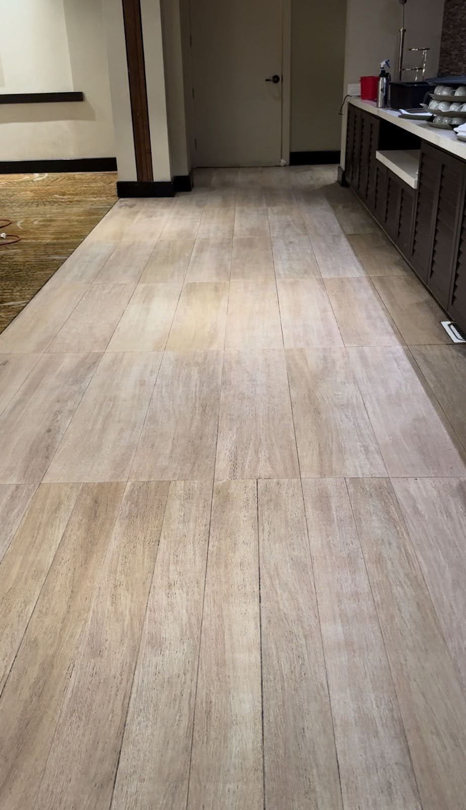 Wood-look tiled floor extending to a doorway. Counter with items on the right.