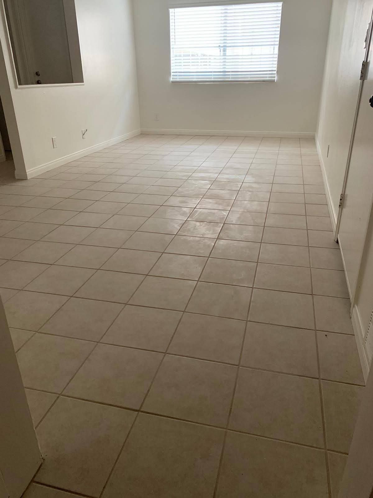 Empty room with beige tiled floor, white walls, and a window with blinds.