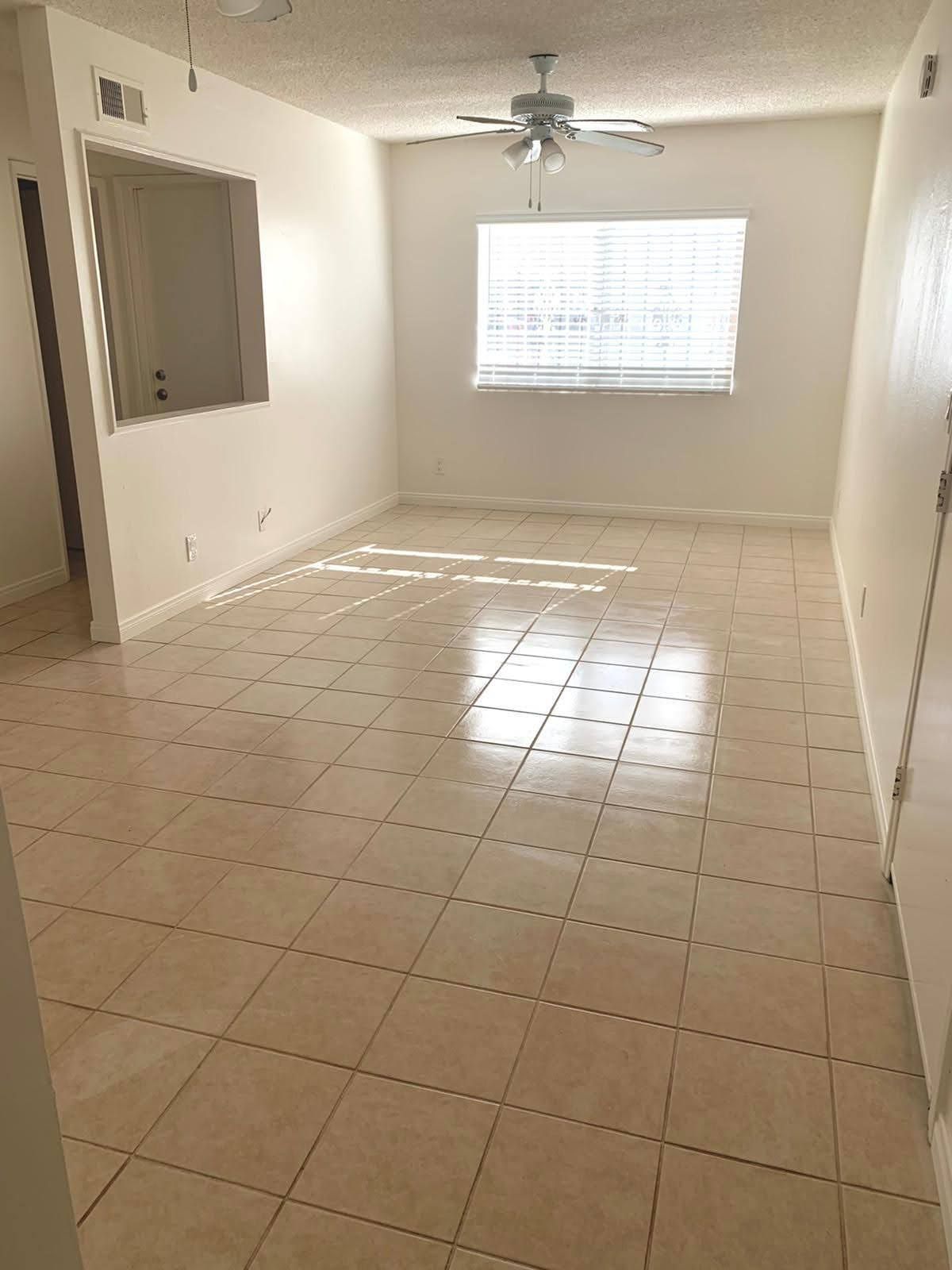 Empty room with tile floor, window, ceiling fan, and open doorway.