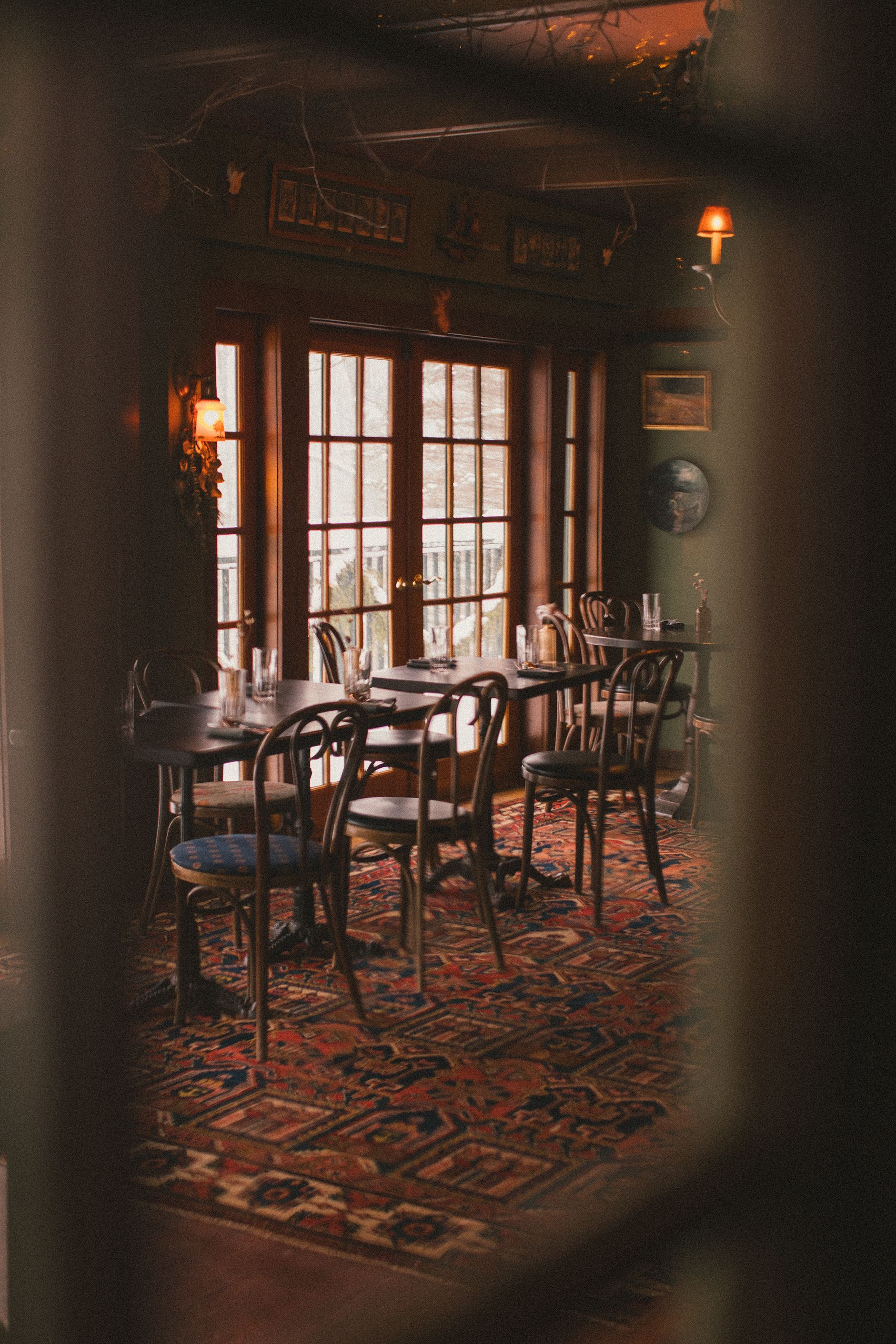 A dining room with tables and chairs and a rug.