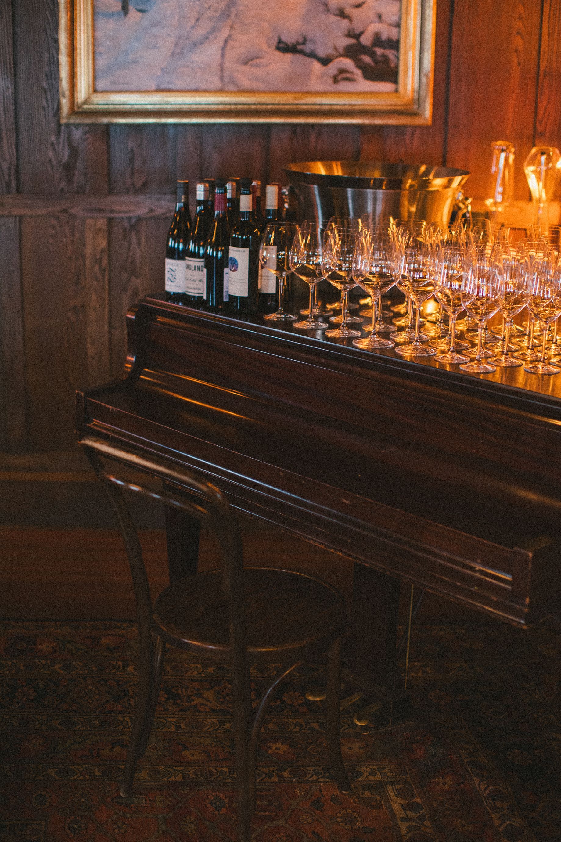 A piano with bottles of wine and glasses on it