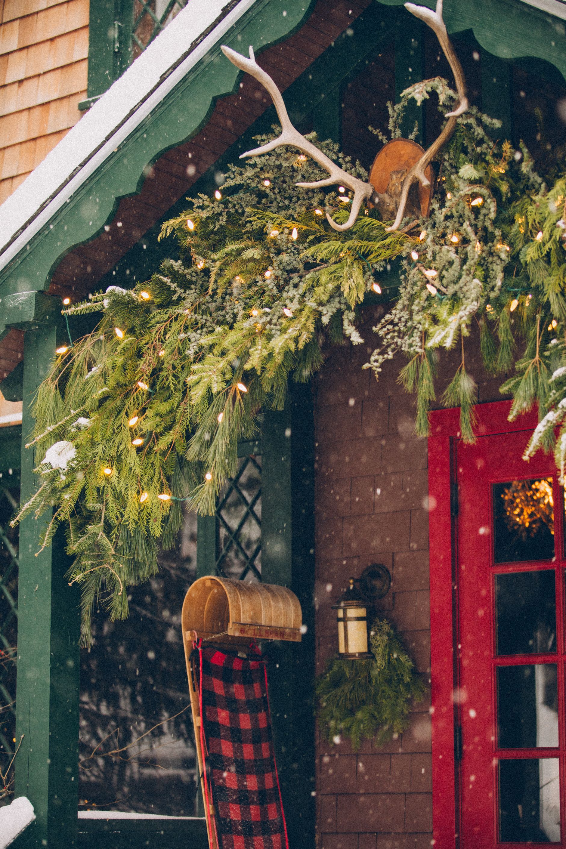 A porch decorated for christmas with antlers hanging from the roof.