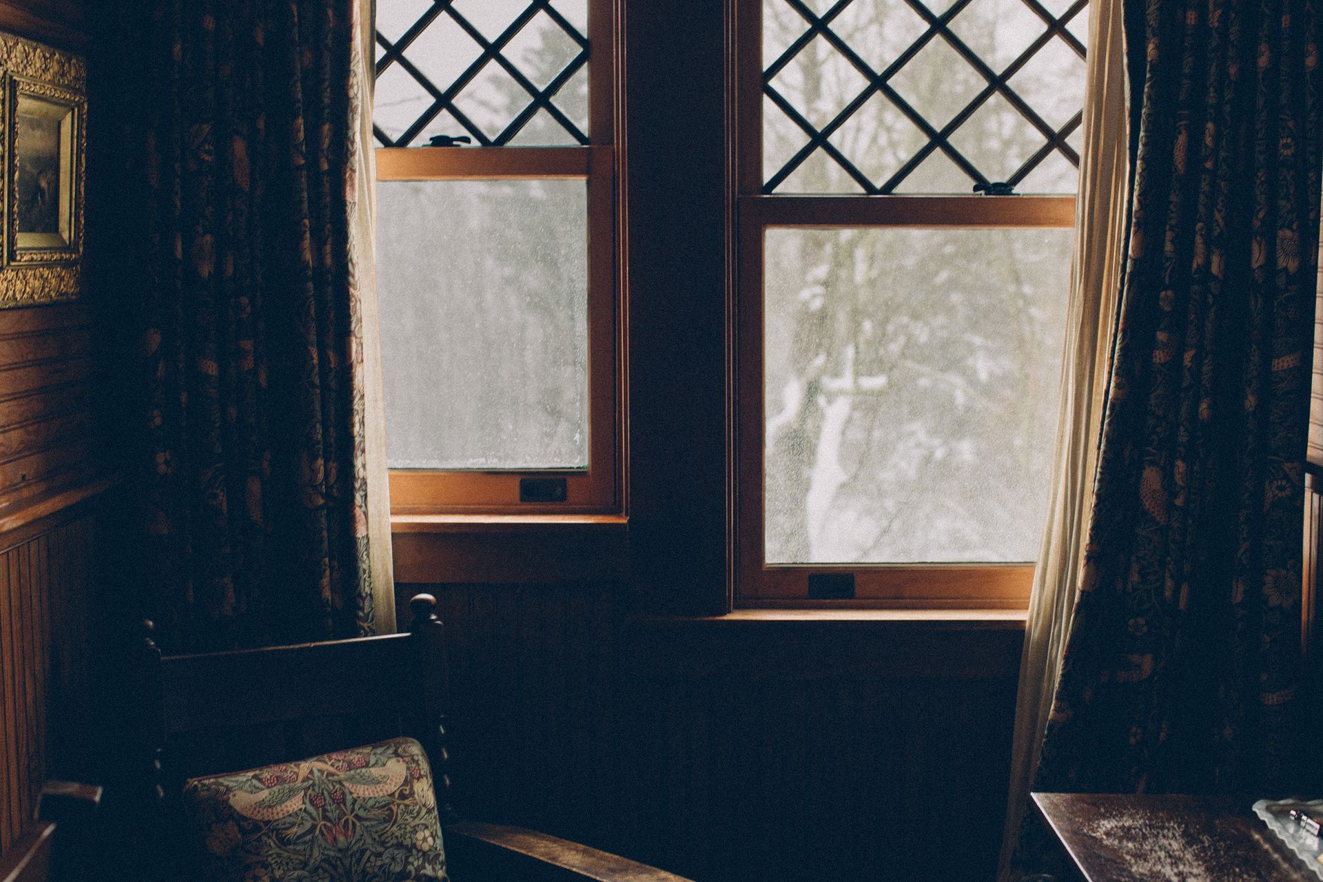 A chair is sitting in front of a window in a dark room.