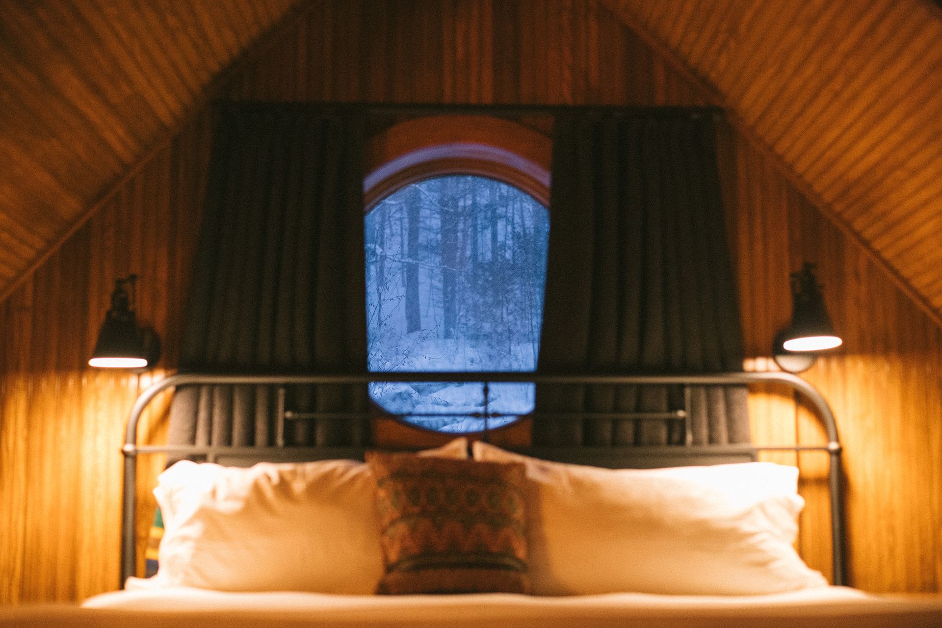 A bedroom with a bed and a window with a view of the woods.