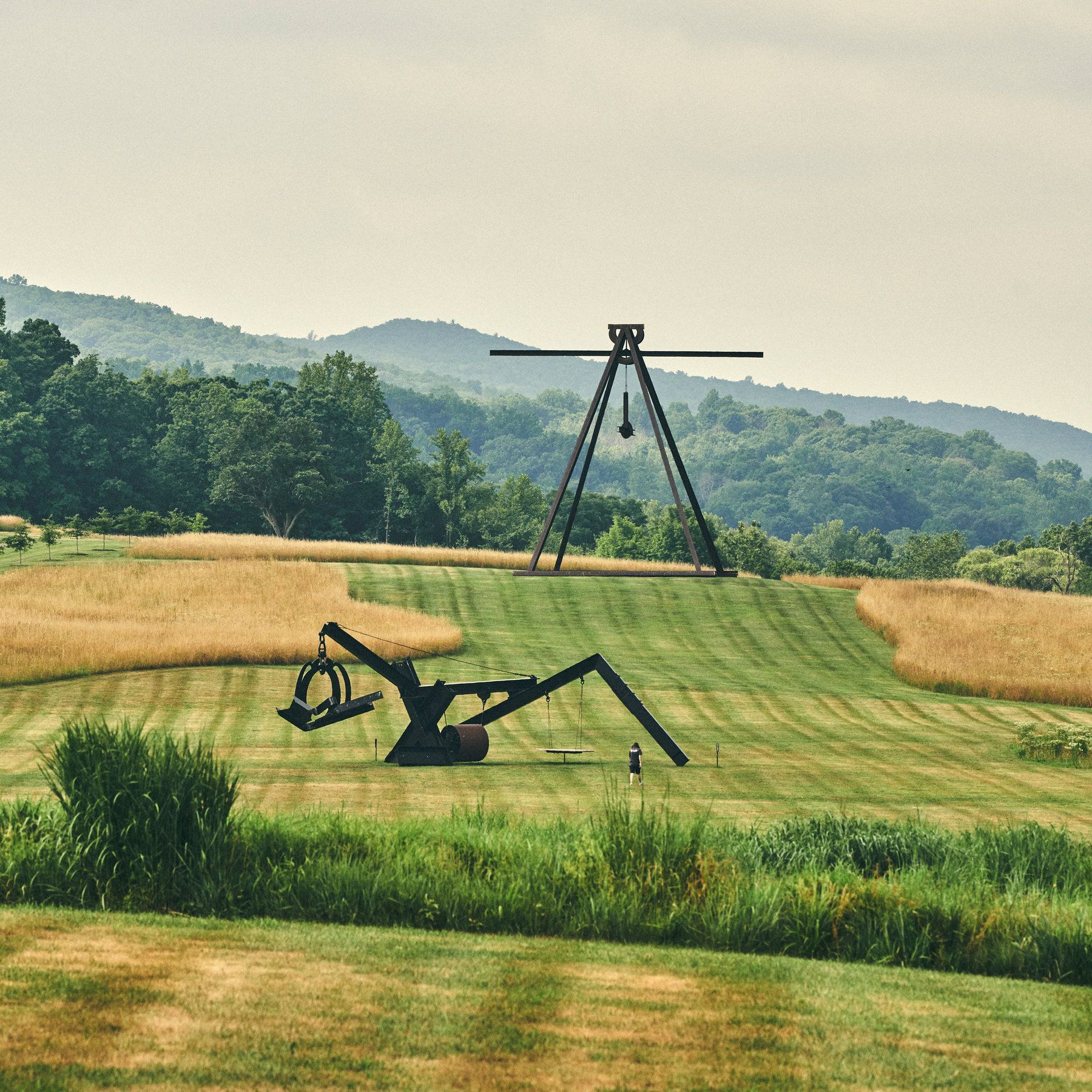 A sculpture in the middle of a field with mountains in the background