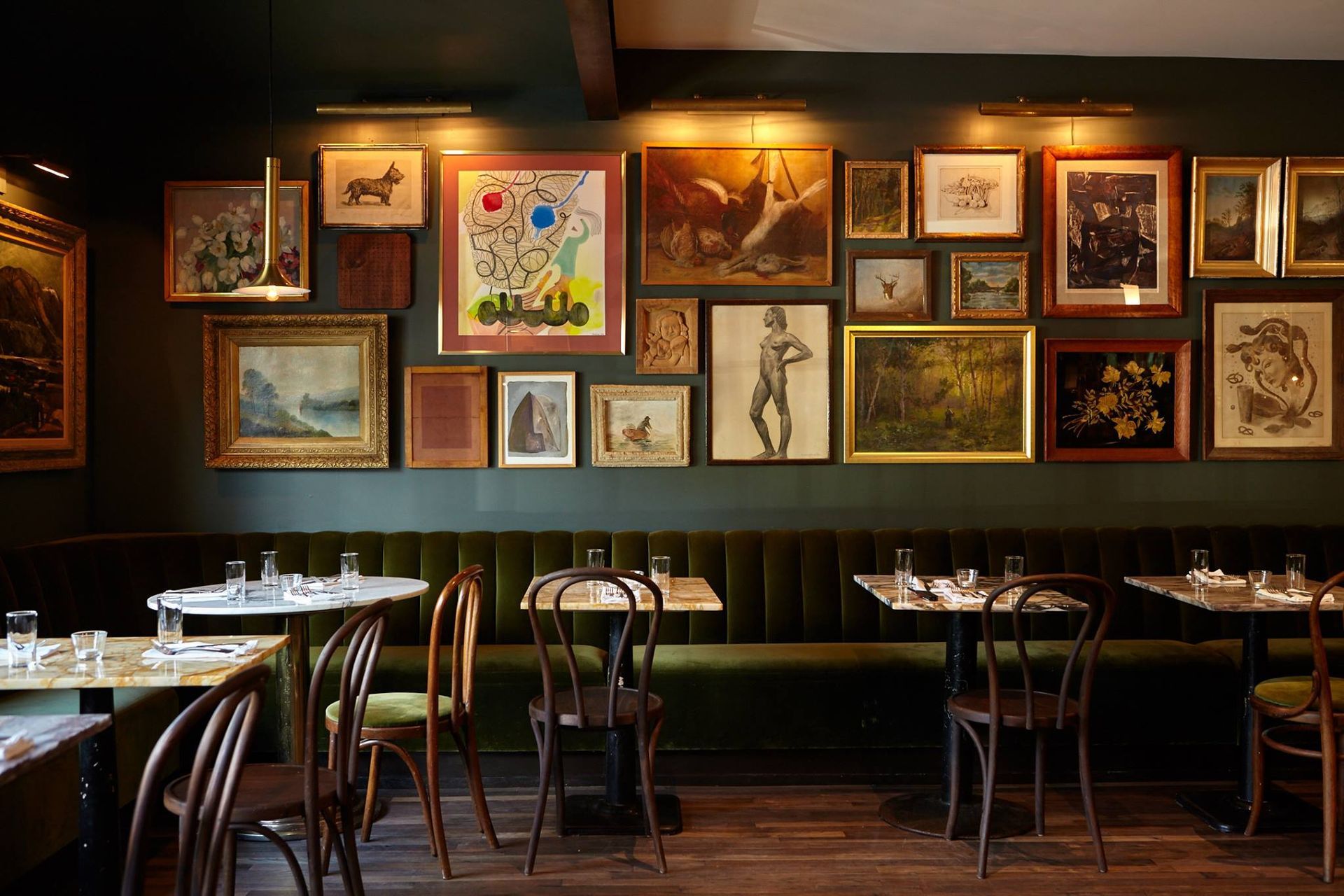 A restaurant with tables and chairs and paintings on the wall.