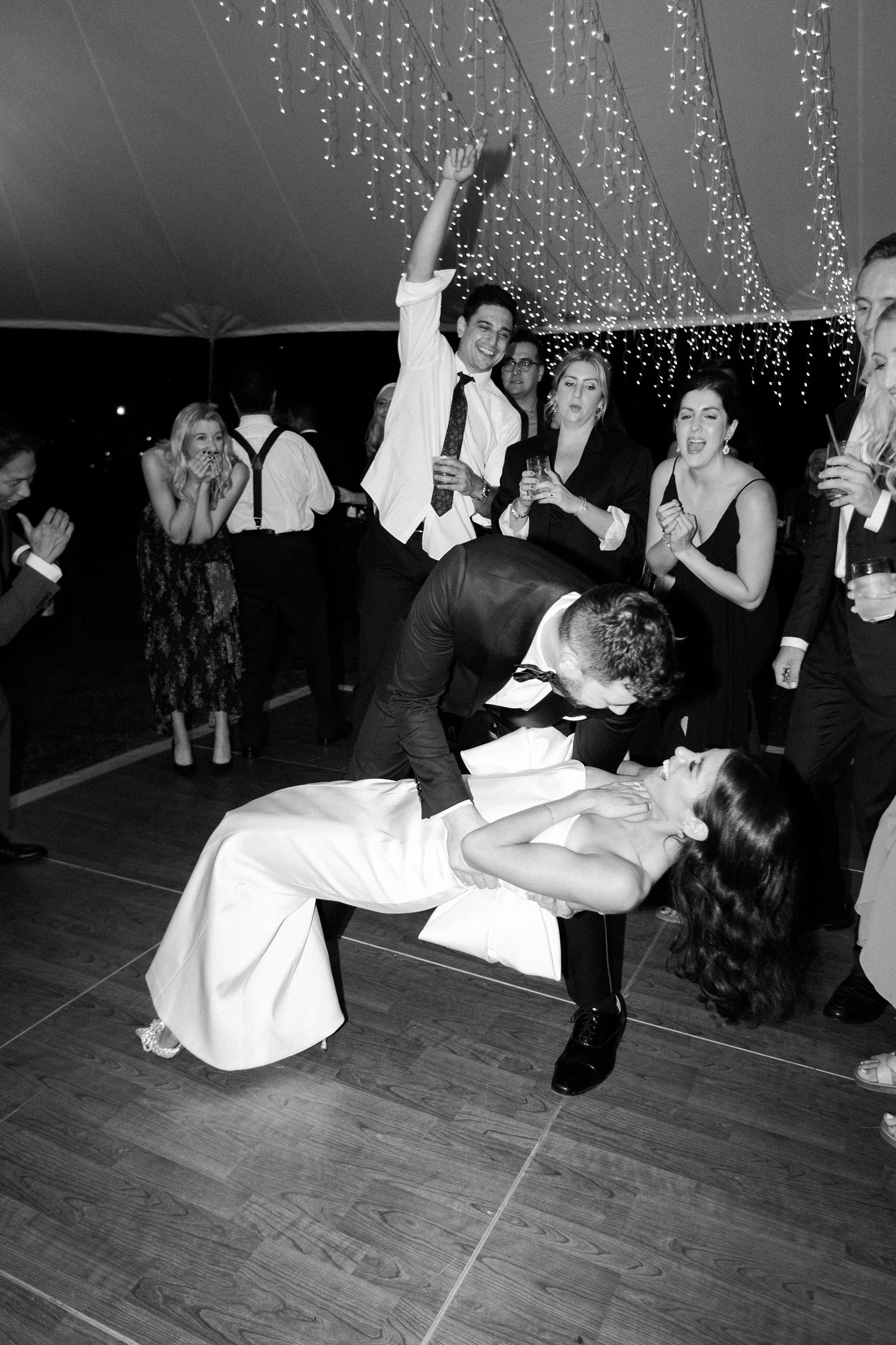 A bride and groom are kissing on the dance floor at their wedding reception.