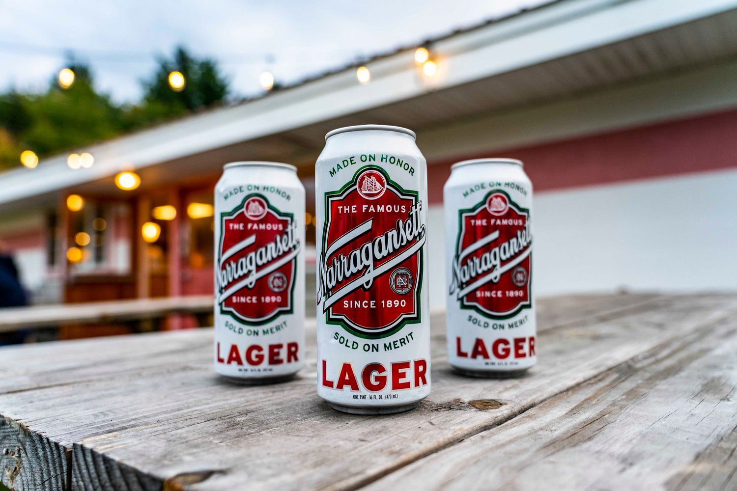 Three cans of lager are sitting on a wooden table.