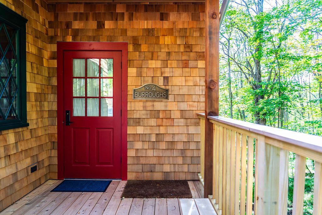 A porch with a red door and a wooden railing.