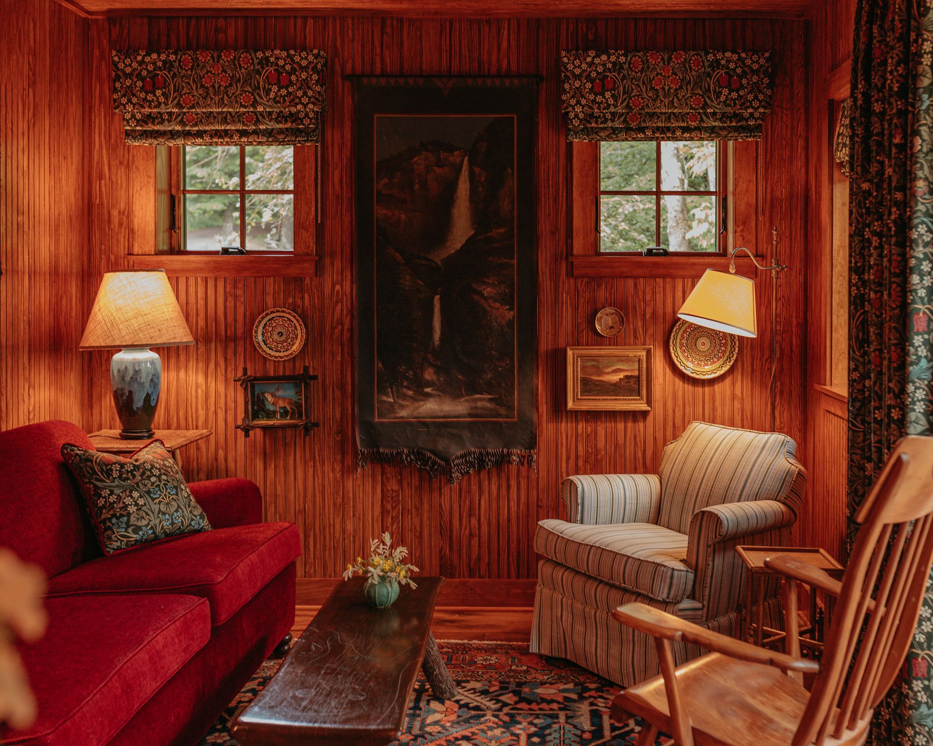 A living room with a red couch and a rocking chair