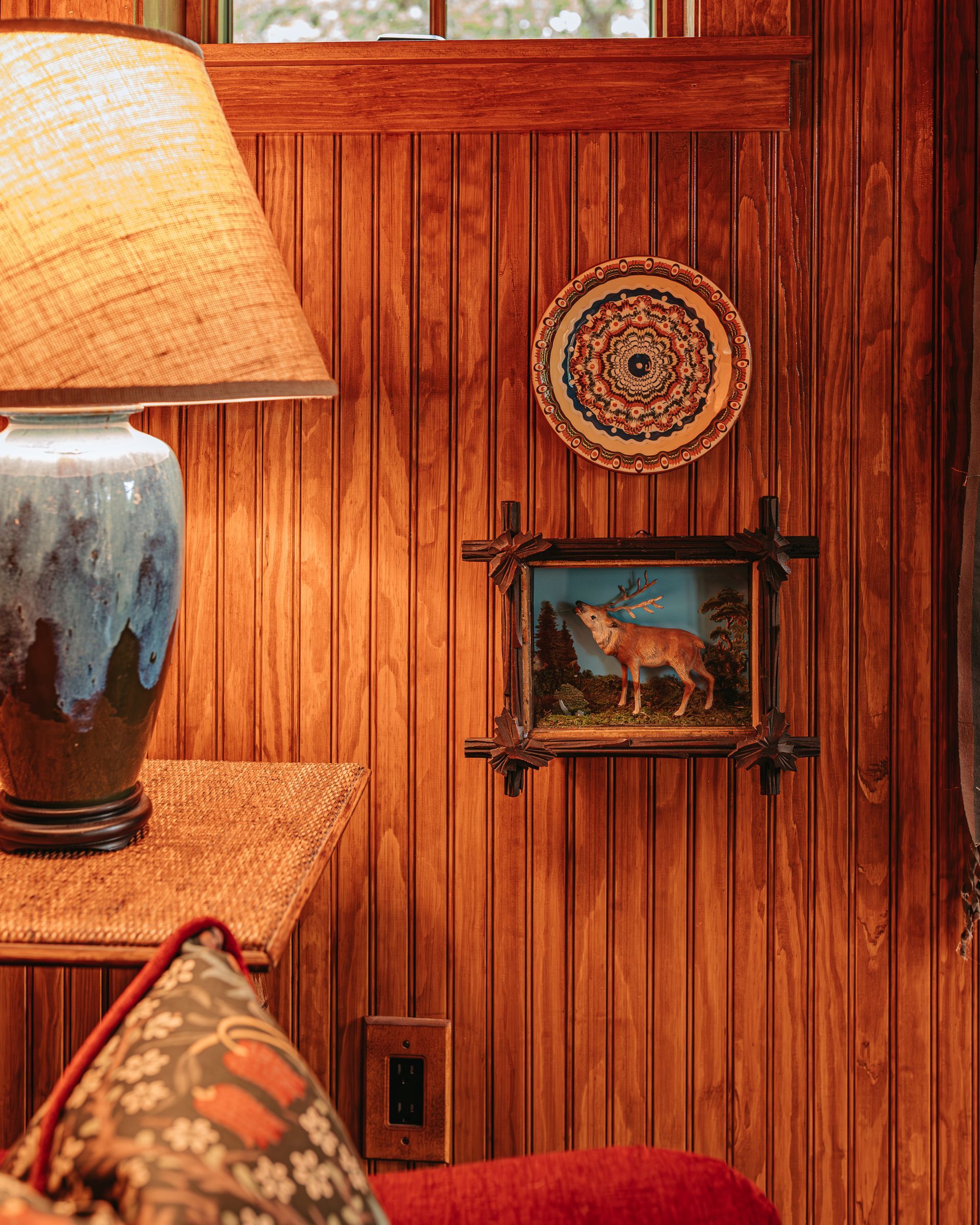 A living room with wood paneling , a lamp , a couch , and a picture on the wall.