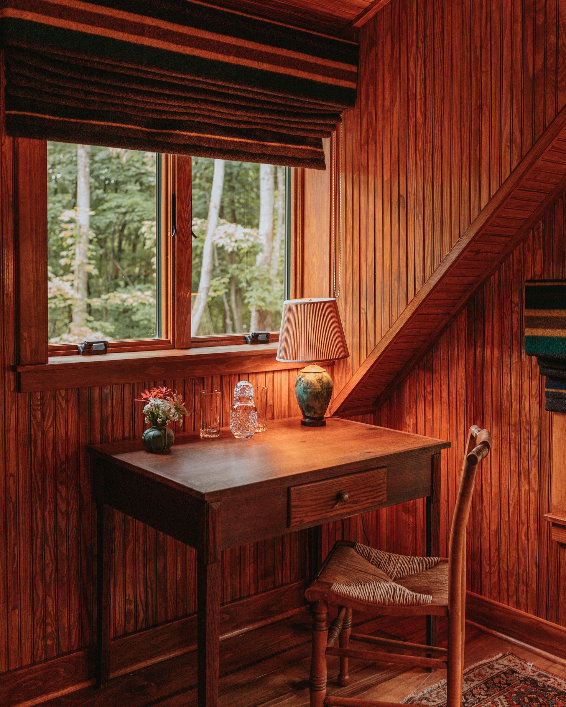 A wooden room with a desk and chair in front of a window