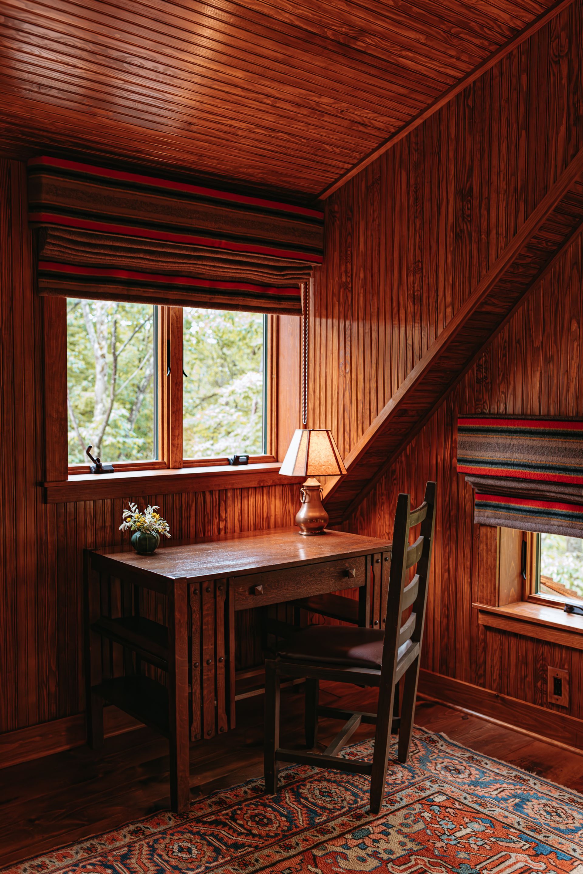 A wooden desk and chair in a room with a window.