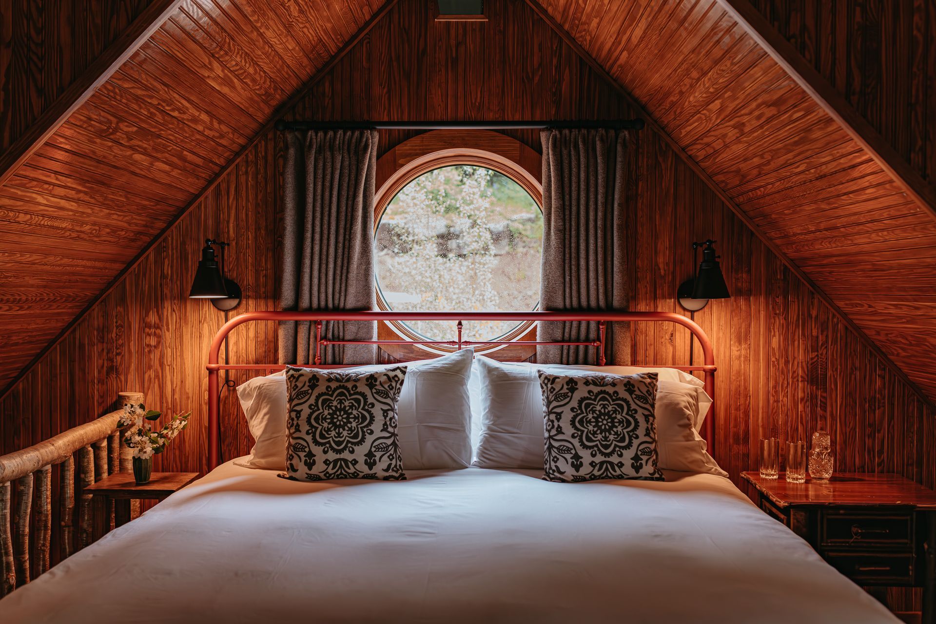 There is a bed in the attic with a round window.