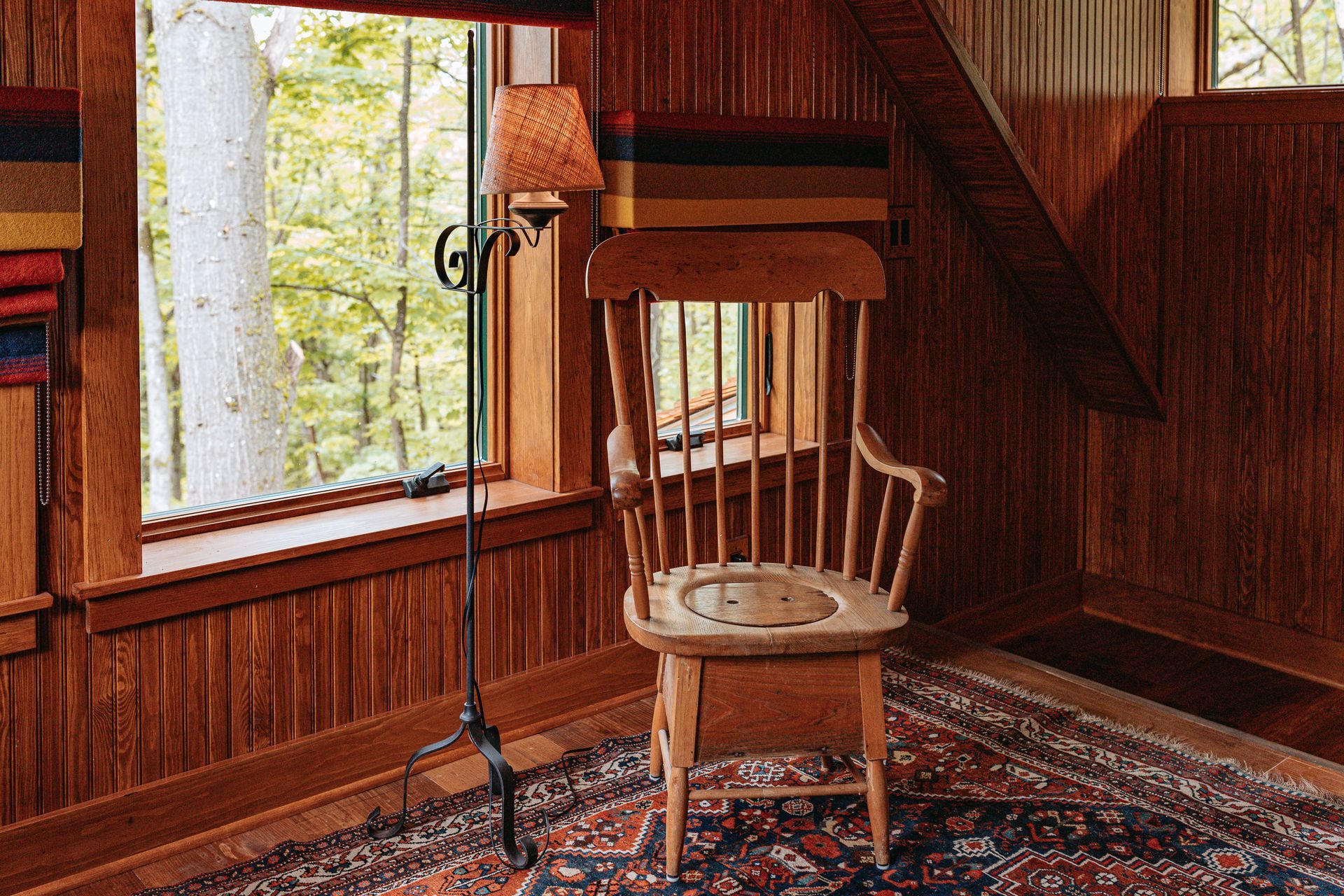 A wooden chair is sitting in a room next to a window.
