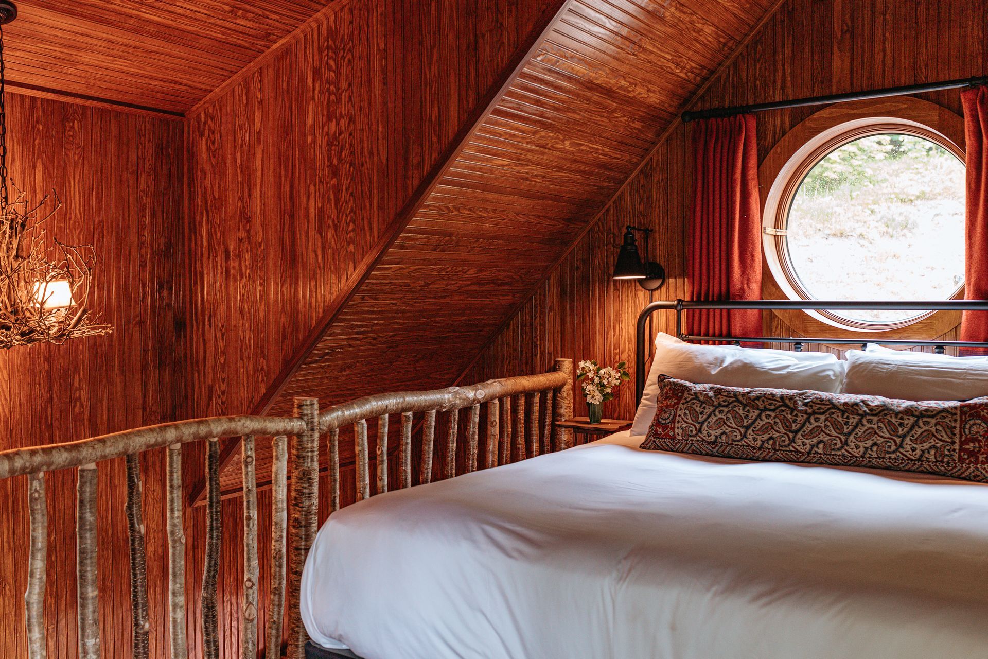 There is a bed in the attic with a round window.