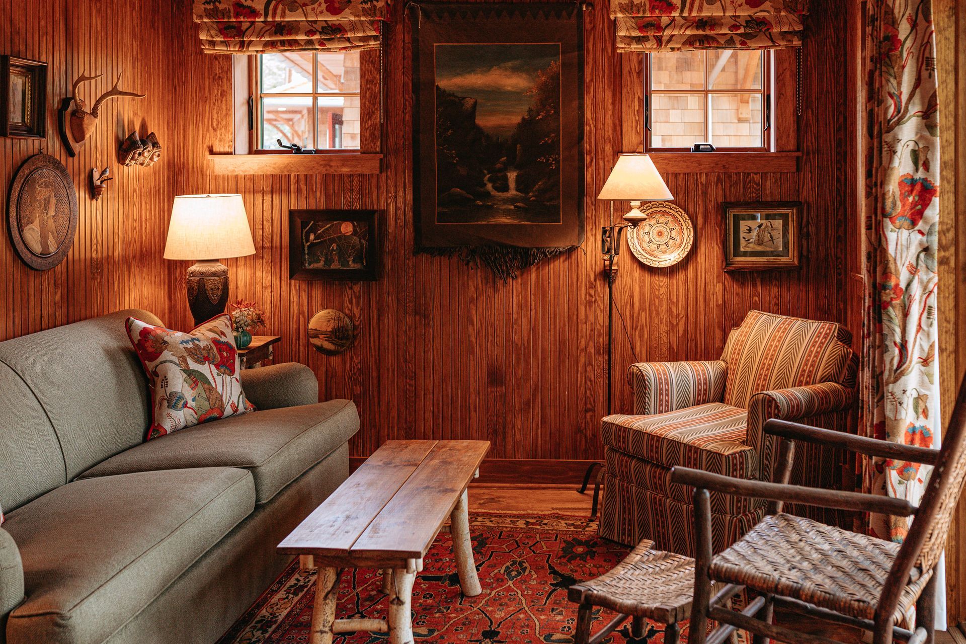 A living room with a couch , chairs , a table and a painting on the wall.