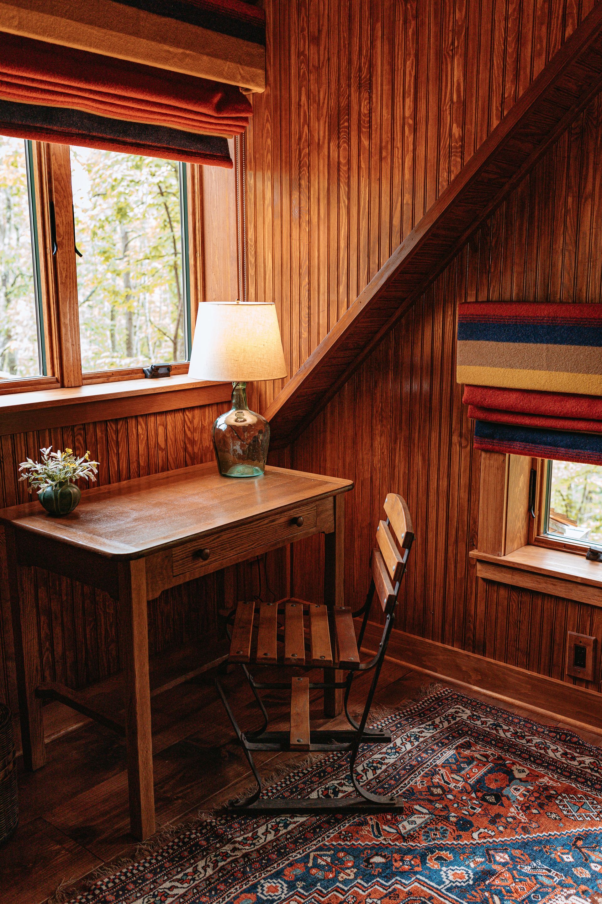 A wooden desk and chair in a room with a rug.