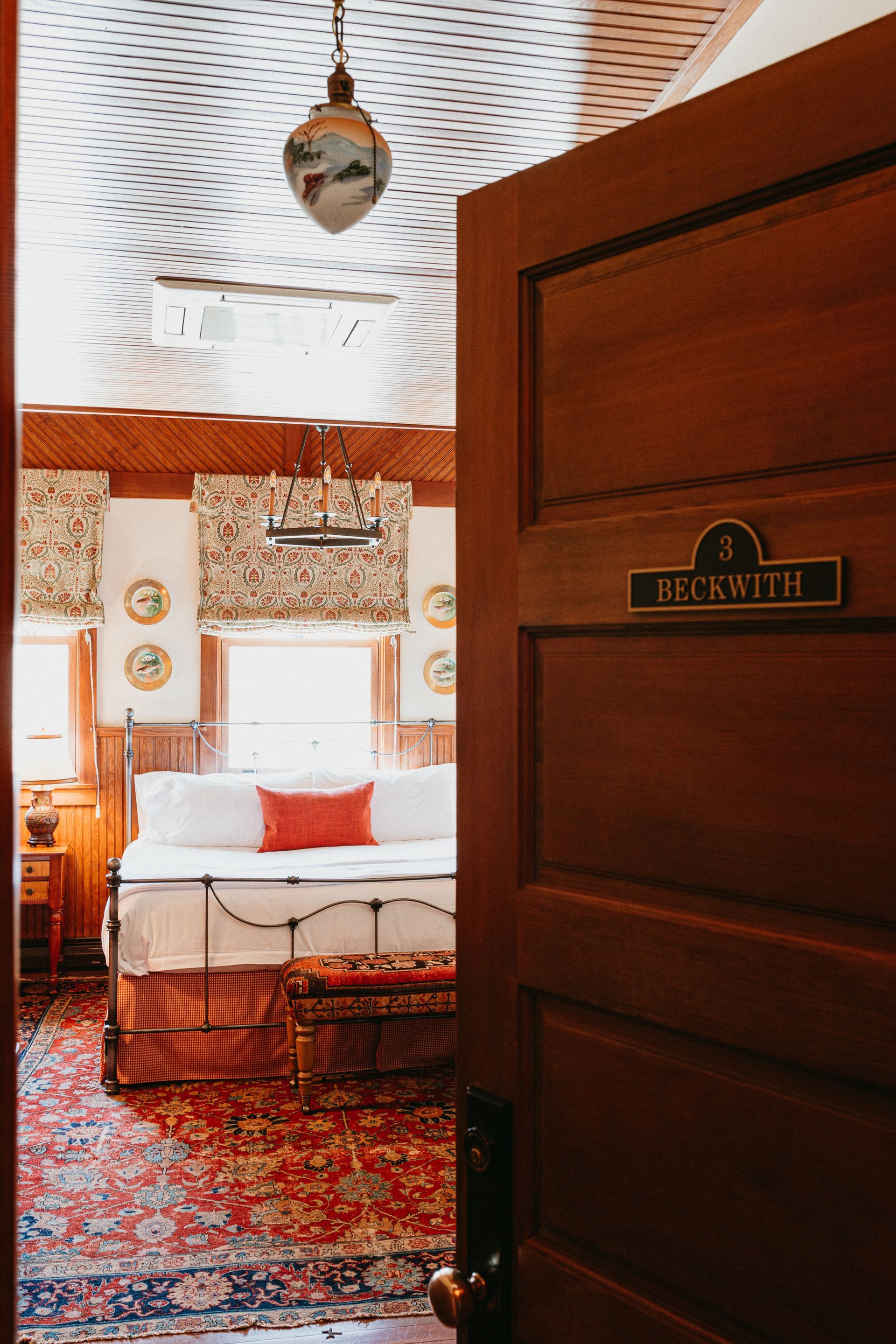 The door is open to a bedroom with a bed and a couch.