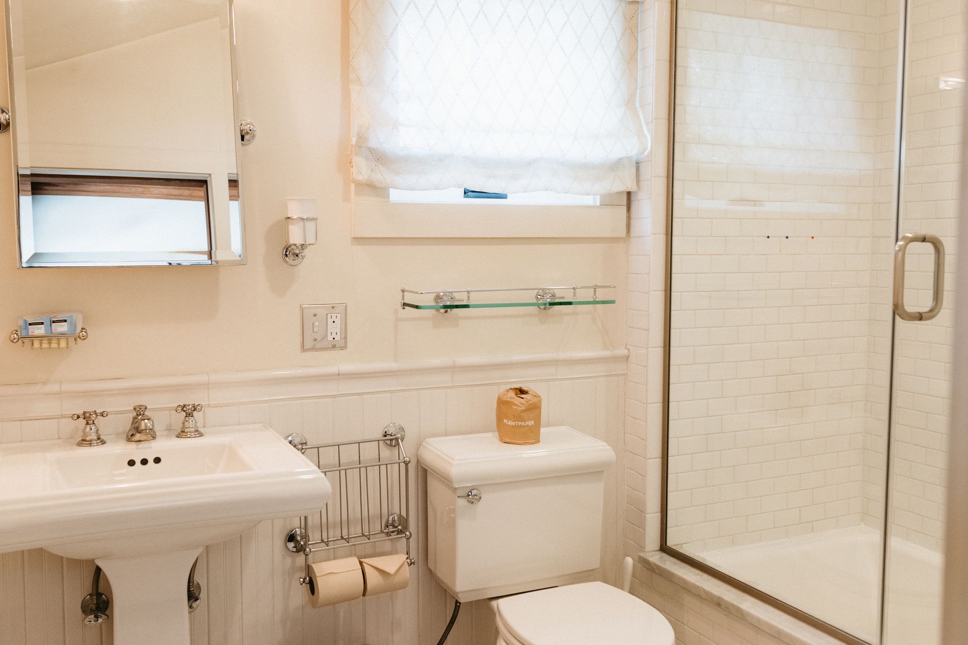 A bathroom with a toilet , sink , mirror and shower.