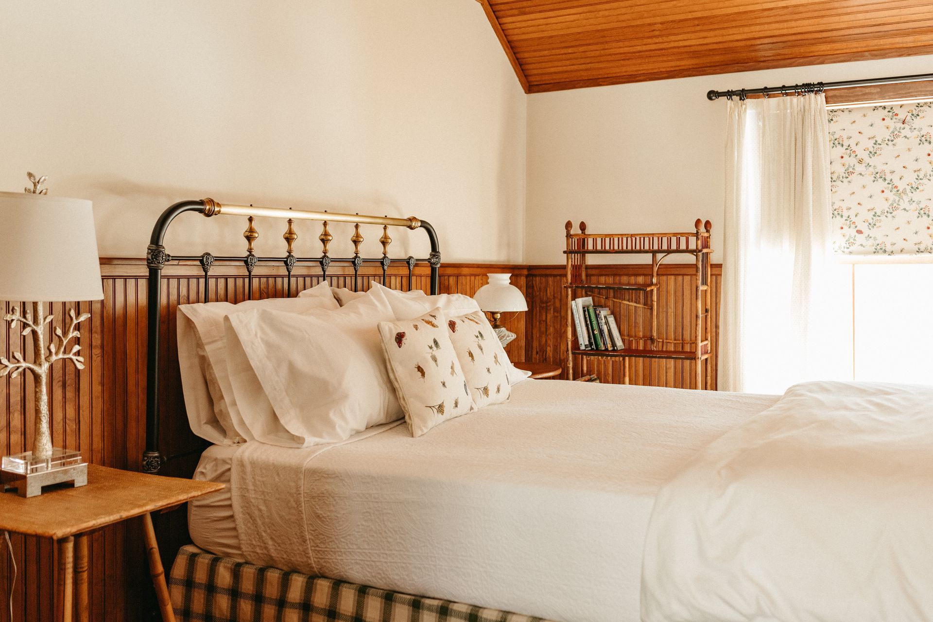 A bedroom with a bed , nightstand , lamp and window.