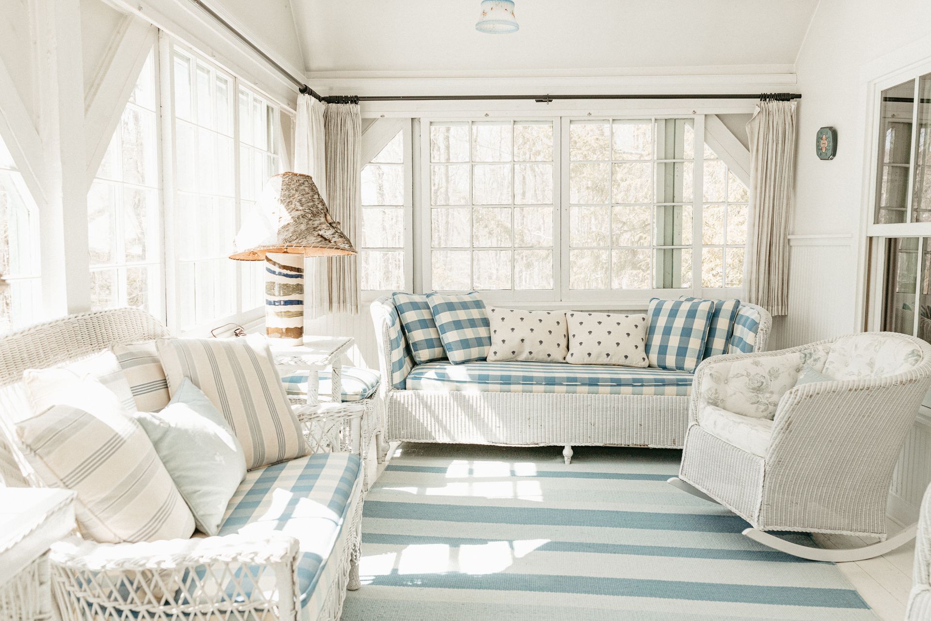 A living room with white furniture and a blue and white rug.