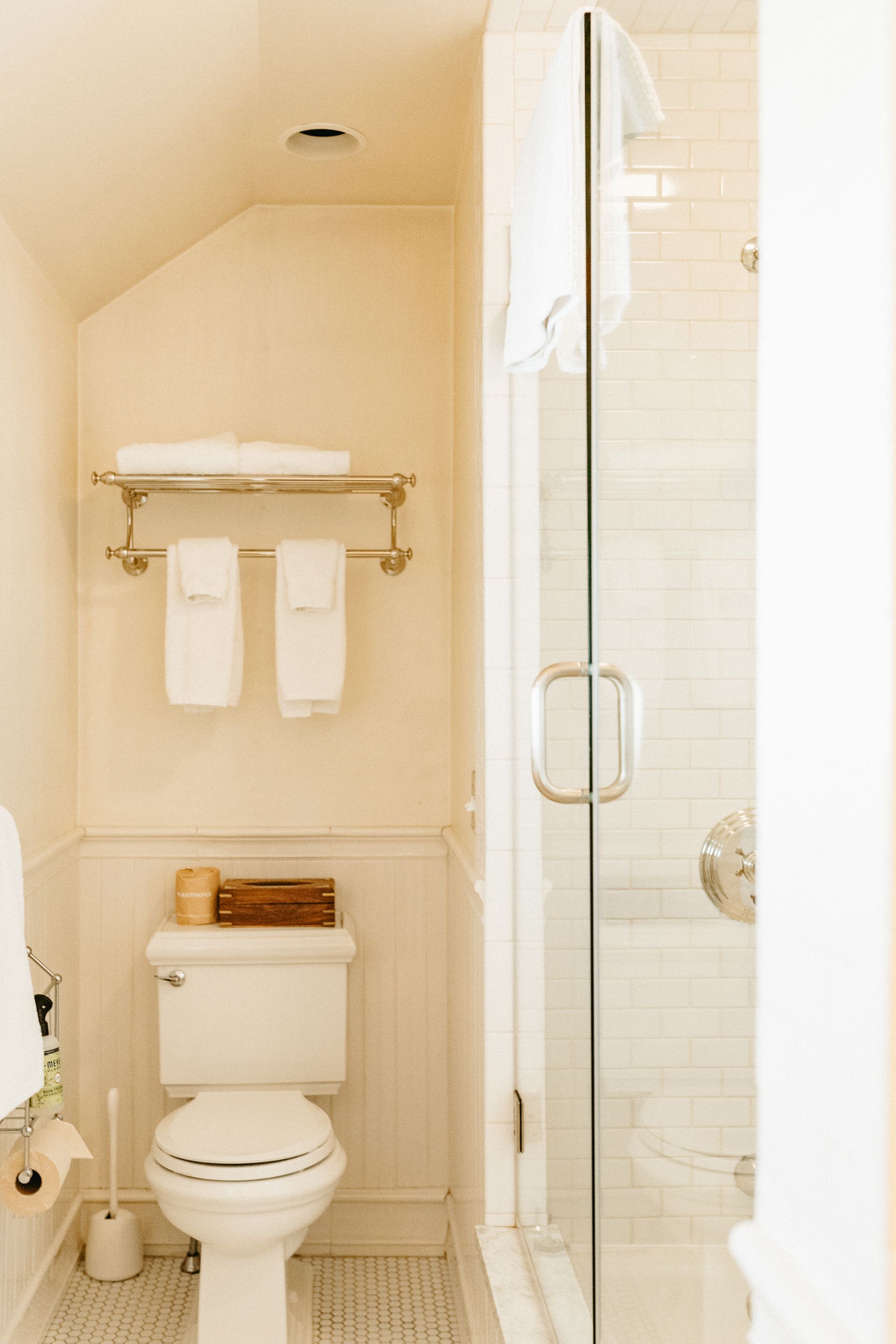 A bathroom with a toilet , shower , and towels.