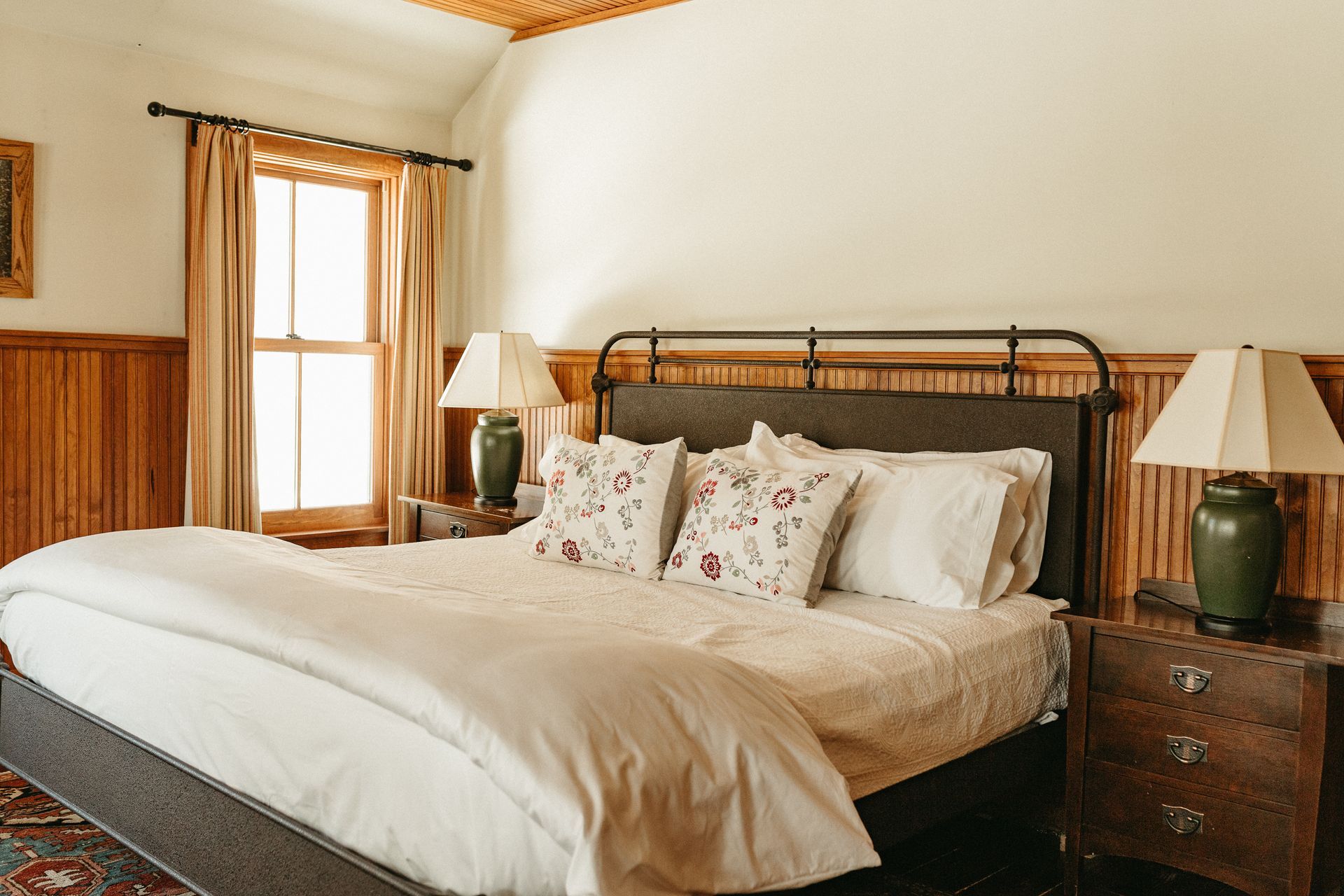 A bedroom with a large bed , two lamps , and a window.