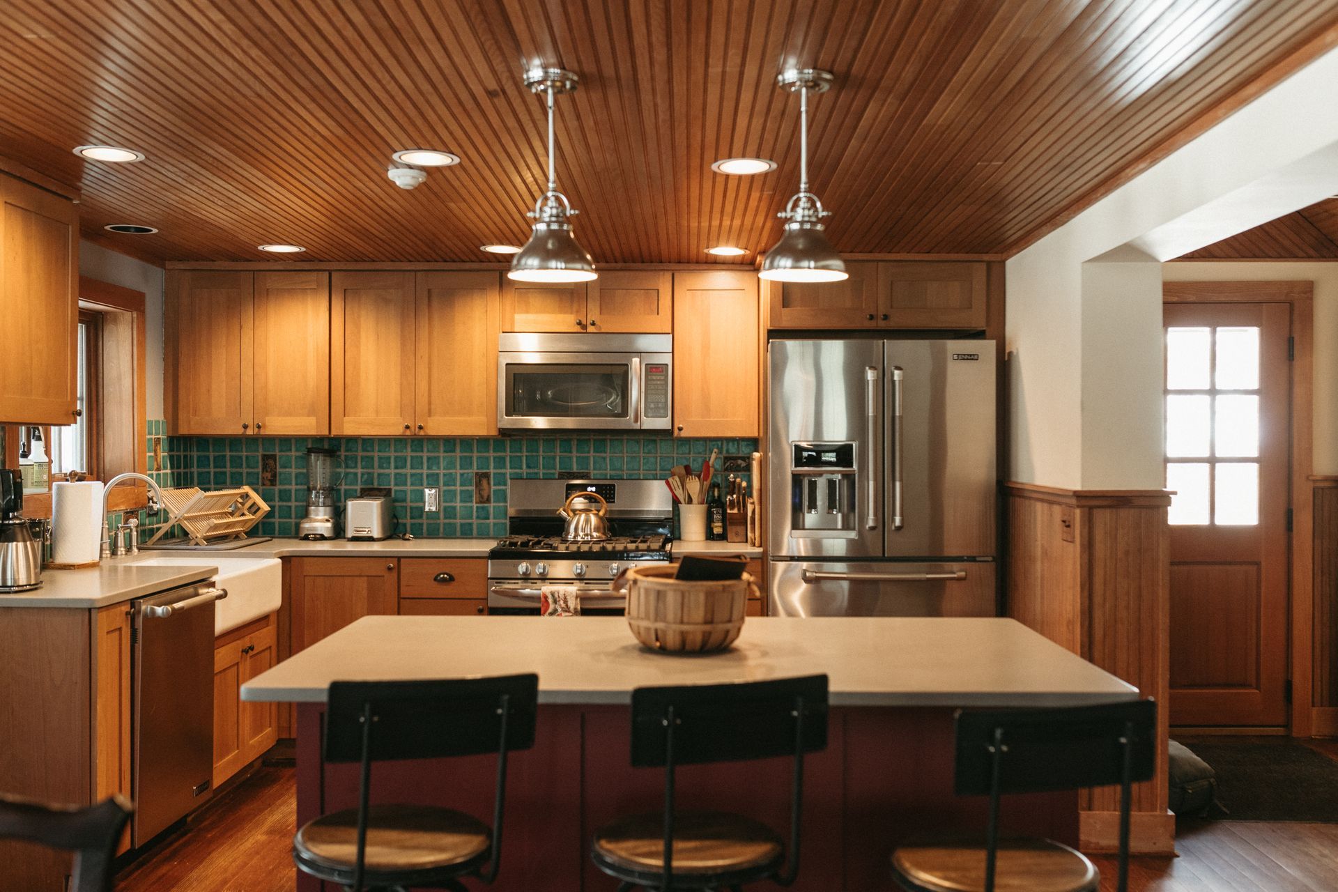 A kitchen with wooden cabinets , stainless steel appliances , and a large island.