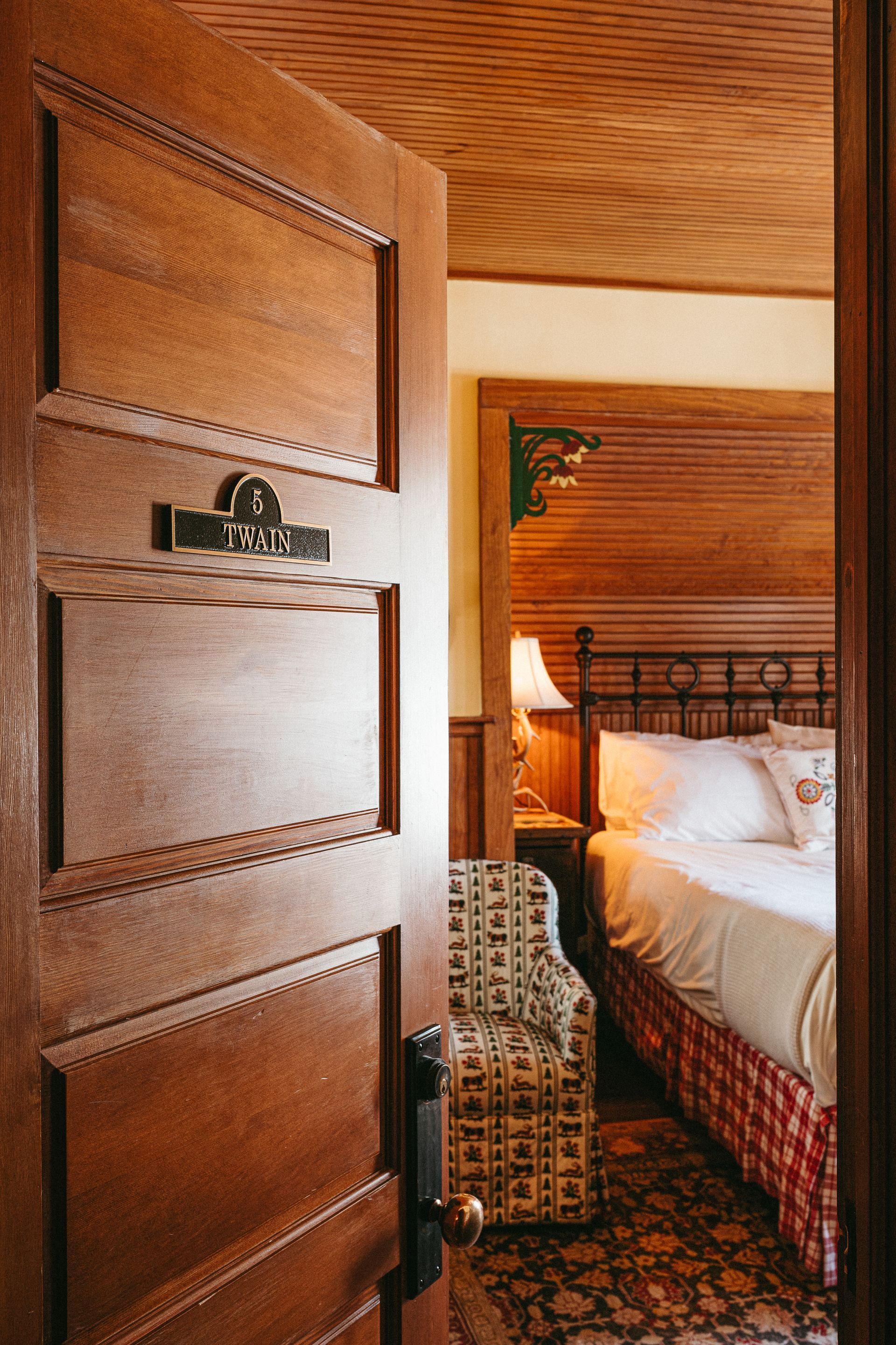 A wooden door is open to a bedroom with a bed and chair.