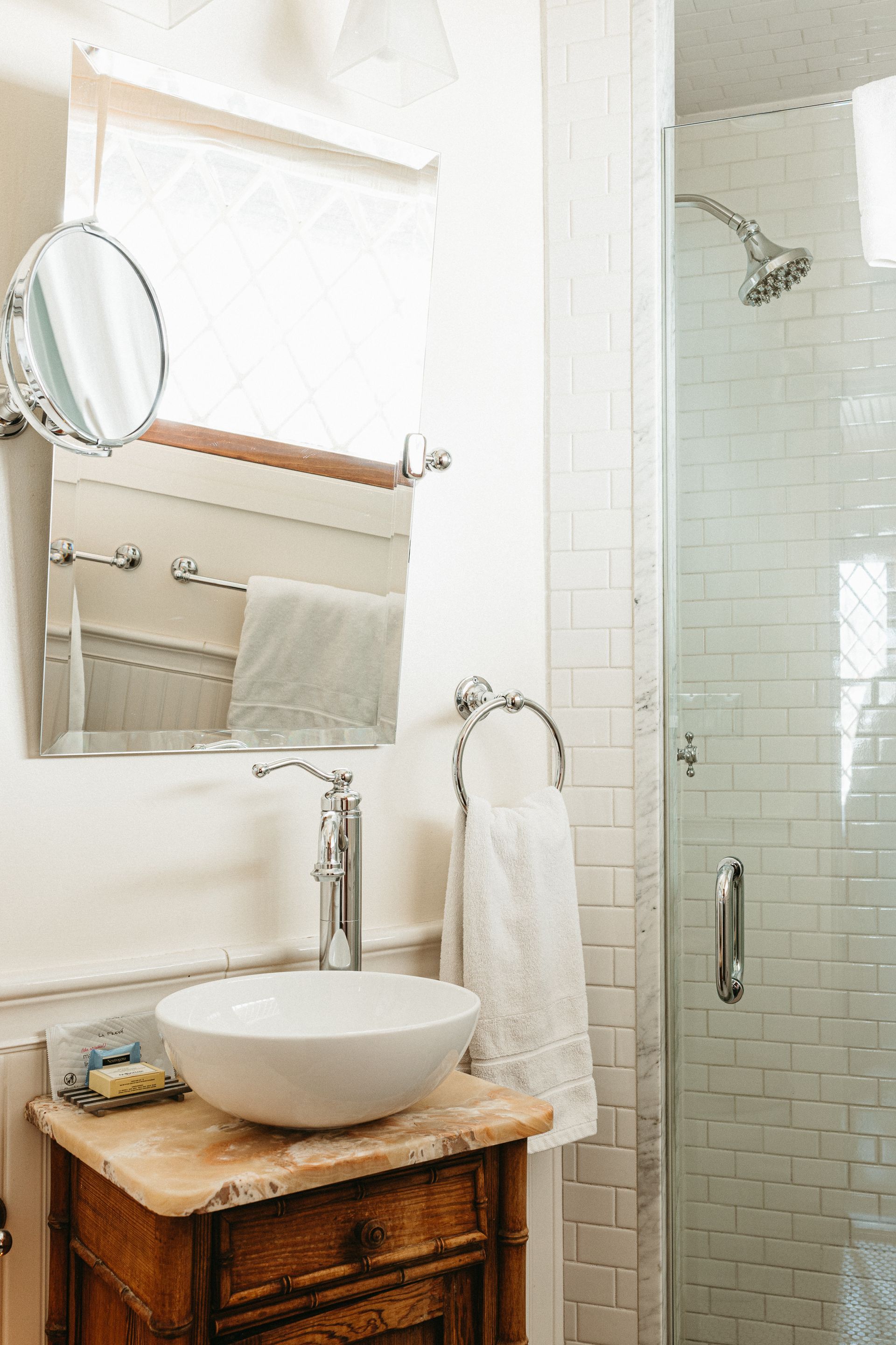 A bathroom with a sink , mirror and shower.
